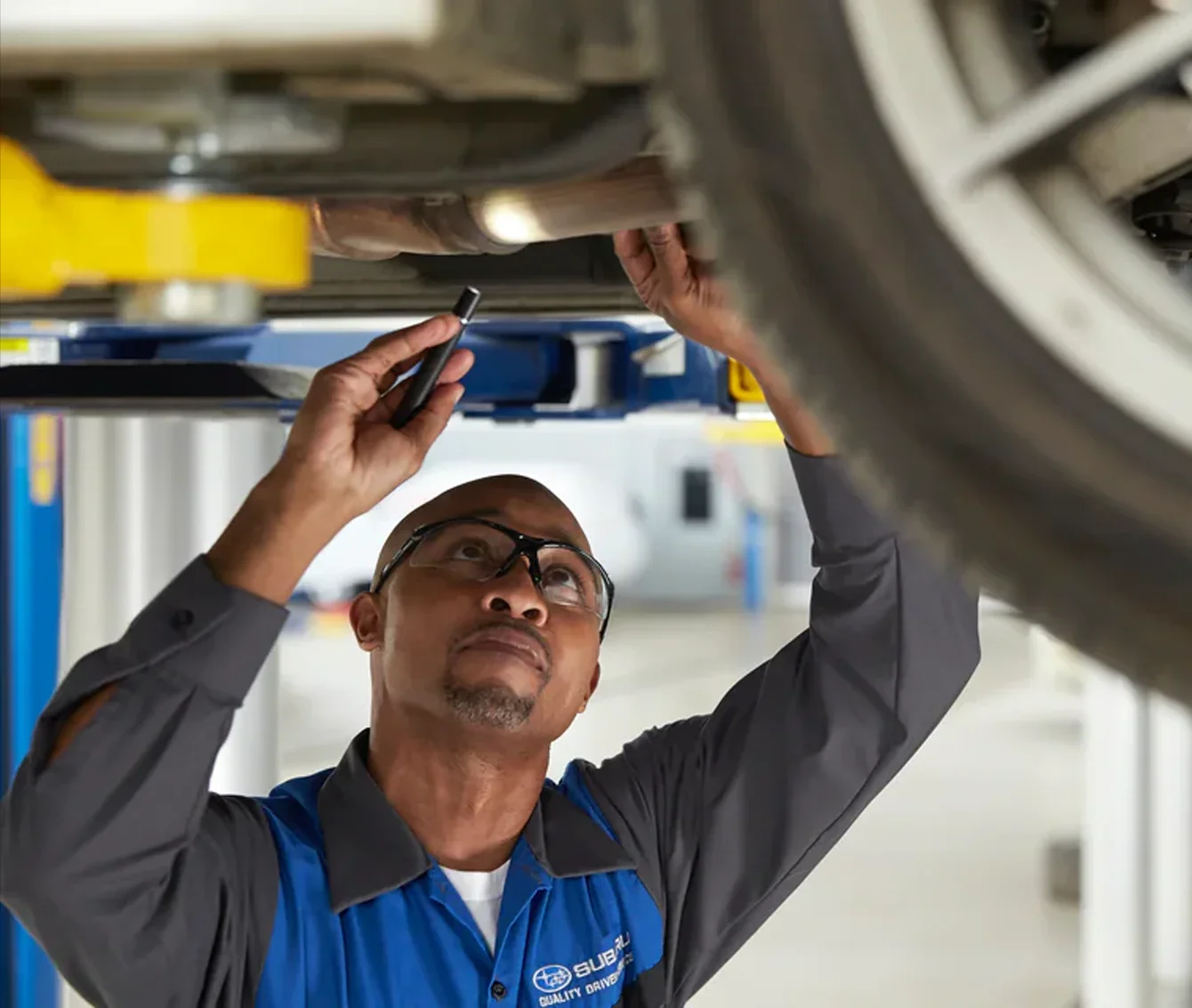 Subaru Service Tech Checking Under Vehicle