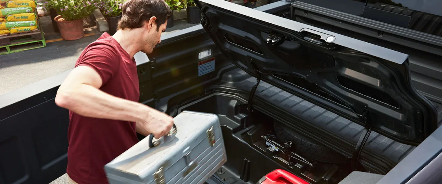 Man loading a toolbox in the back of a Ridgeline