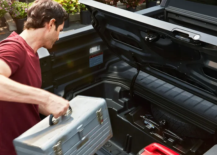 Man loading a toolbox in the back of a Ridgeline